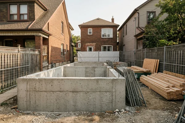 Poured concrete foundation walls for a new fourplex between older Toronto houses